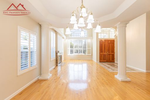 Formal dining area with chandelier, columns, and hardwood floors leading to the grand foyer