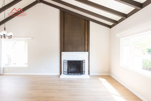 Living room with vaulted open-beam ceiling and wood-burning fireplace