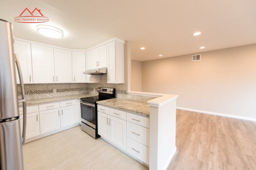 Renovated kitchen with white cabinets, granite countertops, and stainless steel appliances at 1823 El Parque Court #C, San Mateo