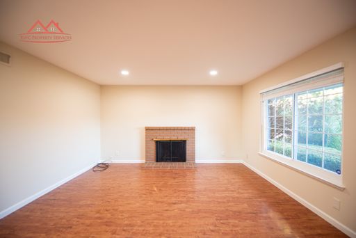 Living room with brick fireplace, laminate flooring, and large window