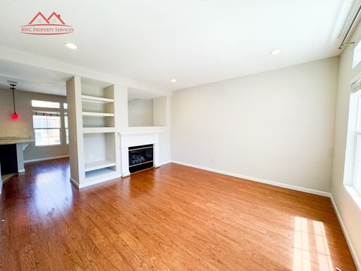 Light-filled living room with hardwood floors, fireplace, and built-in shelving